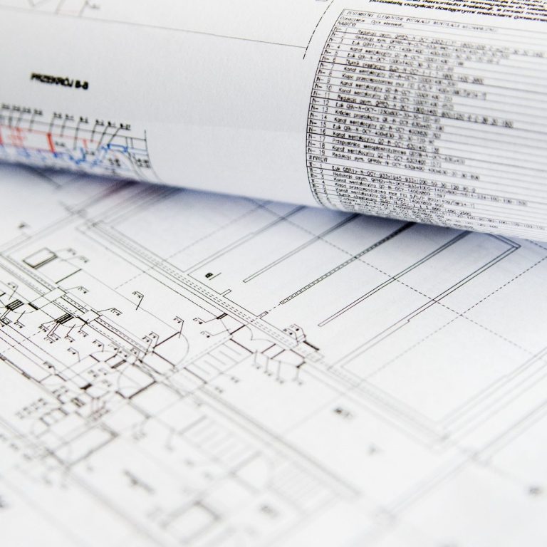 Technische Zeichnungen und Pläne auf gerolltem Papier, teilweise sichtbar.